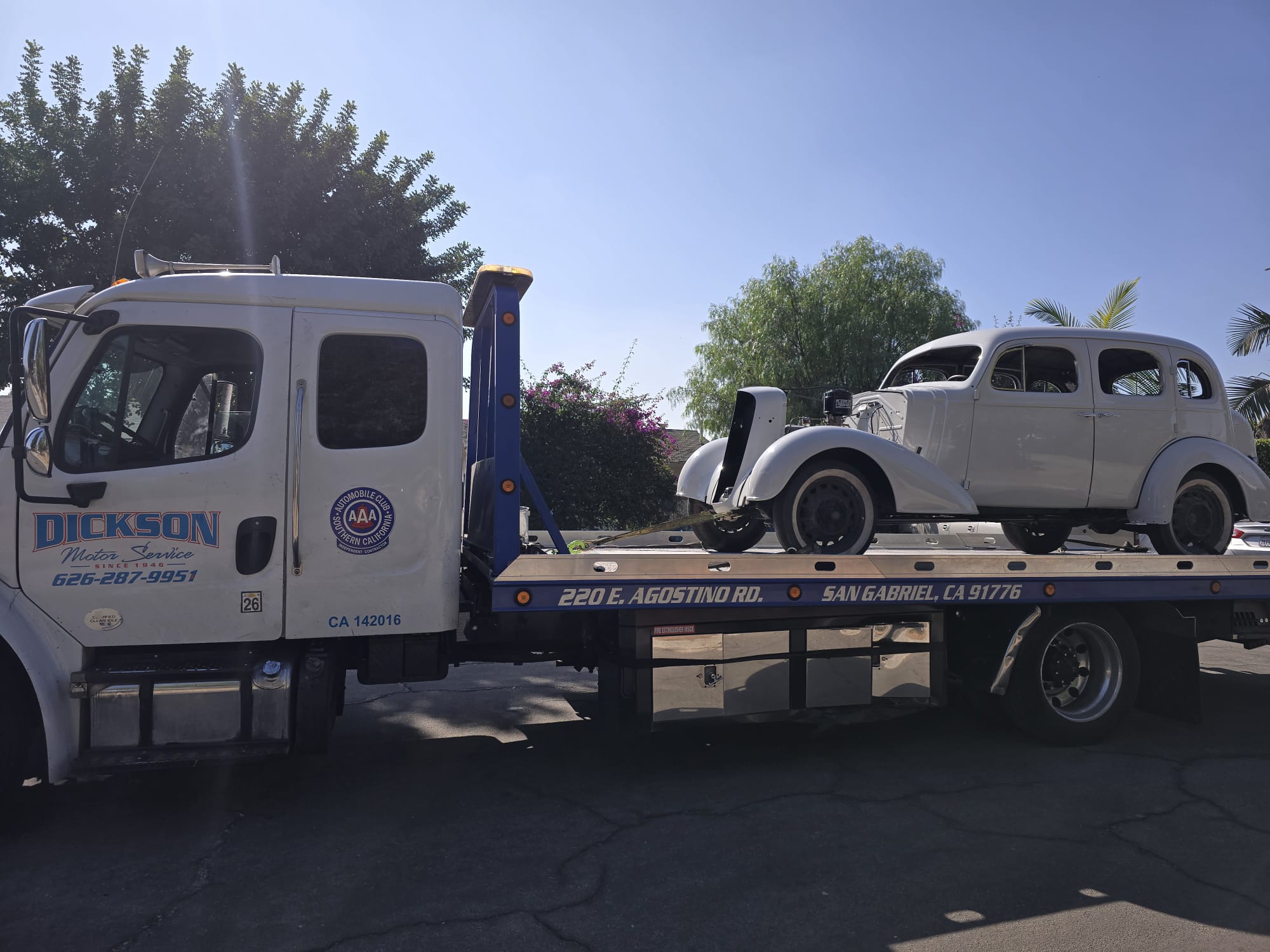 Dickson flatbed transporting a classic vintage sedan in restoration